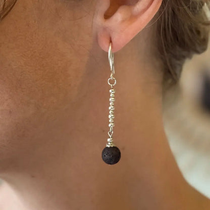 Silver-plated lava stone earrings featuring round black lava stones and silver hooks, stylish and trendy jewelry accessory.
