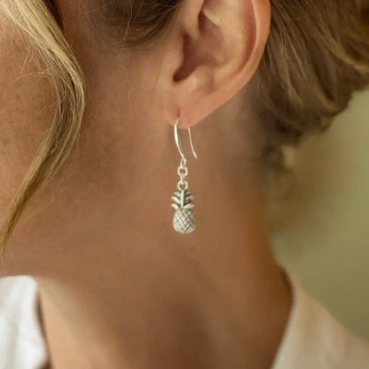 Silver plated pineapple charm earrings by Suzie Blue Canada featuring detailed pineapple designs and dangling earring style.
