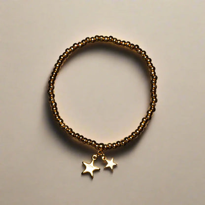 Gold star charm bracelet featuring elasticated design in gold plate, displayed with matching earrings by Suzie Blue Canada.