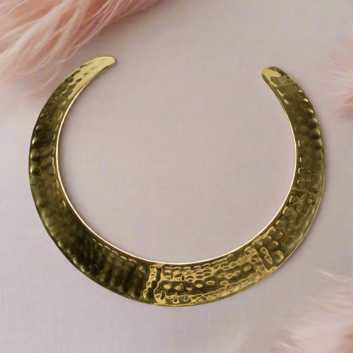 Gold-colored beaten metal collar necklace by Suzie Blue Canada featuring a textured, modern design on a plain background.