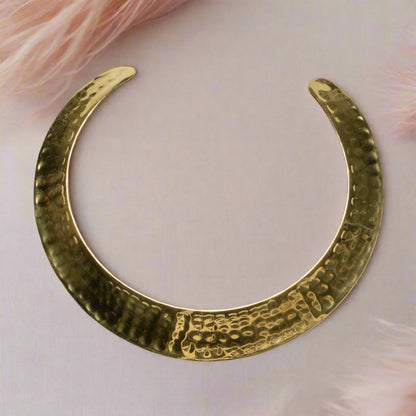 Gold-colored beaten metal collar necklace by Suzie Blue Canada featuring a textured, modern design on a plain background.