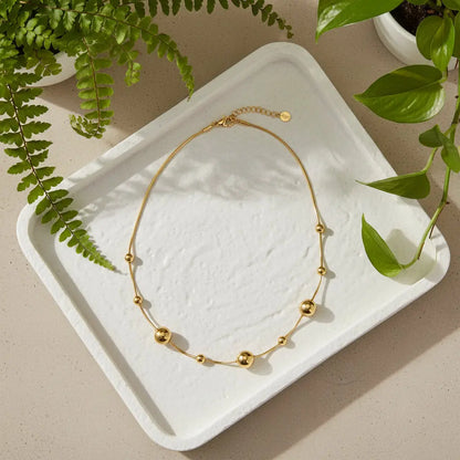 Gold stainless steel Multi Ball Necklace by Suzie Blue Canada, shown in a stylish lifestyle setting.